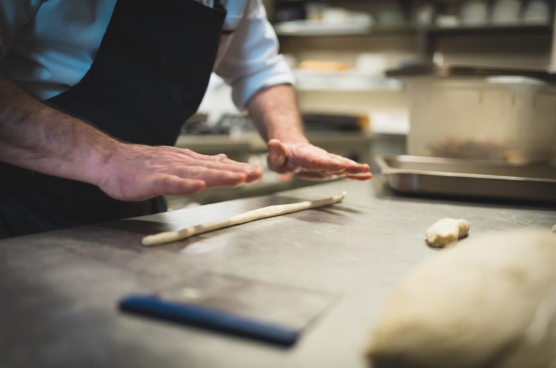 mani del cuoco che preparano grissini artigianali in cucina