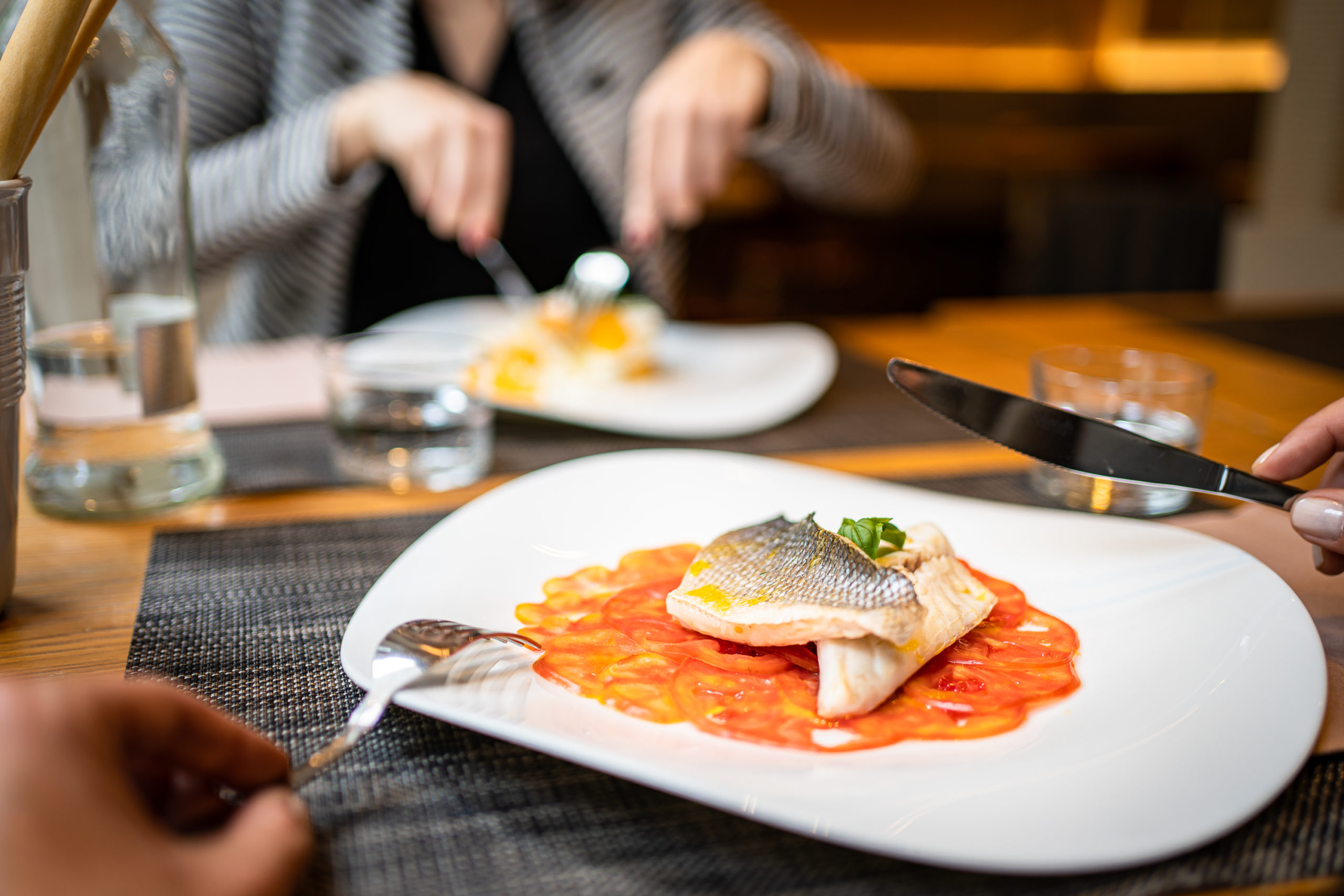 persone che mangiano piatto di pesce a tavola